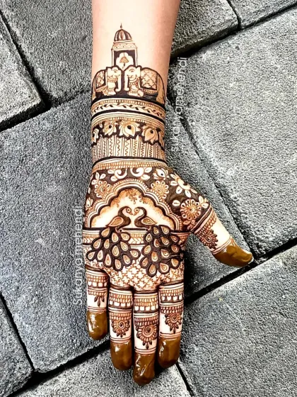 A close-up of the hand from the previous design, showing the detailed elephant and palace artwork on the wrist and the peacock on the palm.