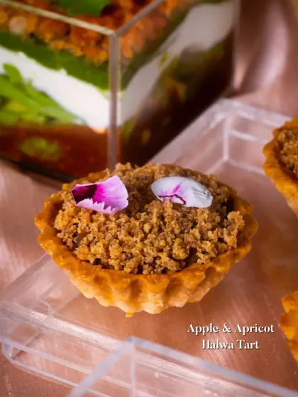 An Apple & Apricot Halwa Tart with a crumble topping. This dessert combines the comforting flavors of apple and apricot with the texture of a traditional halwa and a crunchy crumble.
