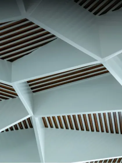 A close-up of the geometric false ceiling, showing the contrast between the white structural elements and the dark wood slats within, adding texture and visual complexity.