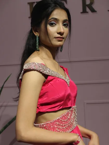 A side view of the pink draped saree, highlighting the off-shoulder blouse and the intricate work on the belt.