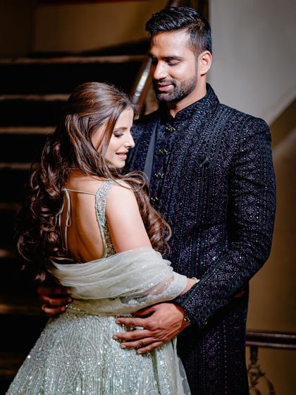A full-length portrait showing the couple's elegant reception attire and their comfortable, loving posture.
