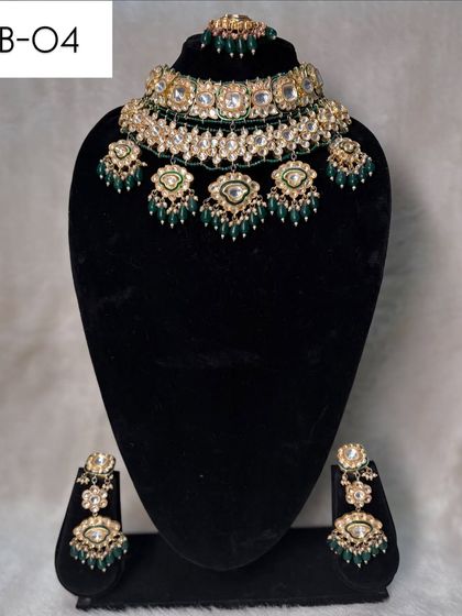 A beautiful choker set, B-04, featuring polki stones and hanging green bead details. This rental set is perfect for adding a touch of color and tradition.