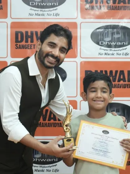 A teacher presents a trophy to a young, happy student for his creative painting.