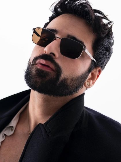 A portrait of creative entrepreneur Varun Vig for Lenskart, modeling a pair of stylish square-frame sunglasses.