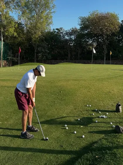 A close-up of a golfer practicing his chipping, with a bucket of balls ready for a long session.