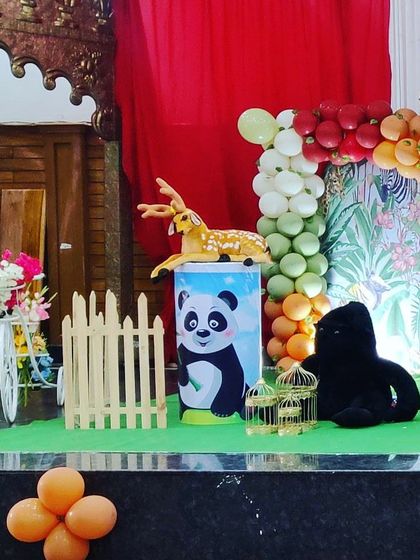 A detailed shot of a jungle-themed decor corner. It features a panda-themed plinth, stuffed animals like a deer and gorilla, and wooden 'BABY' blocks, adding to the wild animal theme.