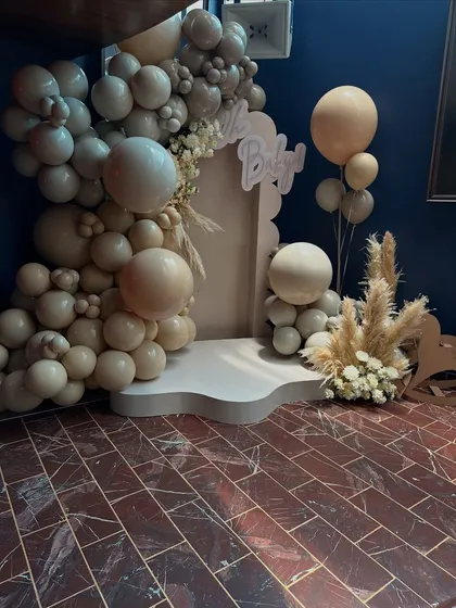 Another angle of the chic "Oh Baby" photo booth, highlighting the texture of the organic balloon garland against the dark wall.