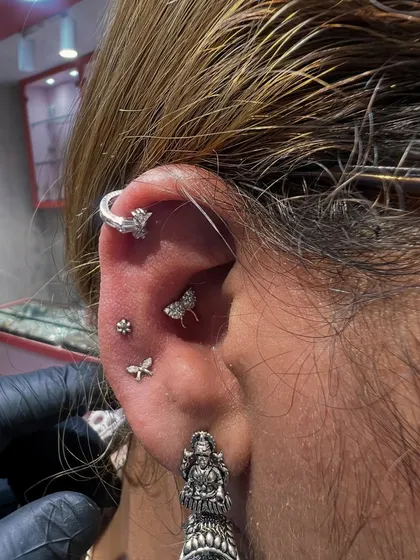 A beautifully curated ear in all silver, featuring a helix hoop, a bee stud, a dragonfly, and a floral piece, finished with a traditional oxidized jhumka.