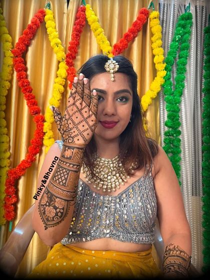 A bride ready for her mehndi ceremony, showing off her beautiful back hand design. The grid pattern and floral cuff are elegant and timeless.