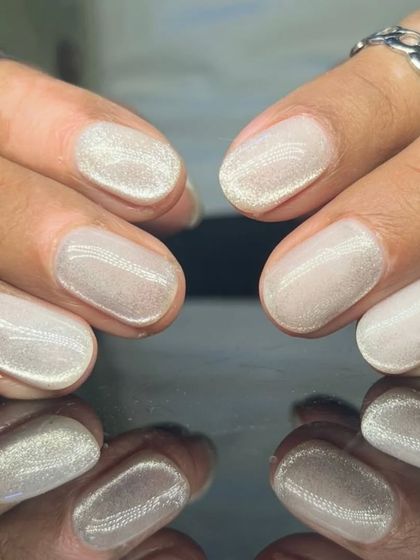 A beautiful, shimmery white cat-eye polish on short, rounded nails for a subtle and magical look.
