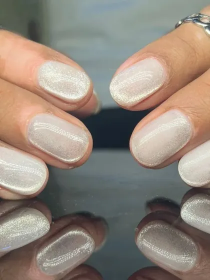 A beautiful, shimmery white cat-eye polish on short, rounded nails for a subtle and magical look.