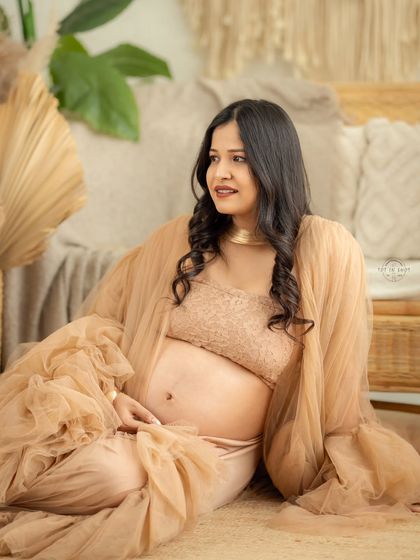 A candid, seated portrait capturing the gentle glow of motherhood in our warm, boho-inspired studio setting.