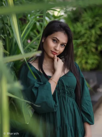 A portrait of a model in a dark green tiered dress, framed by lush foliage. The composition creates a sense of being immersed in nature.