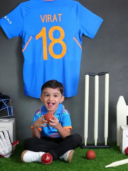 A future cricket star. This toddler is having a blast in our cricket-themed setup, complete with a Virat Kohli jersey, bat, ball, and wickets.