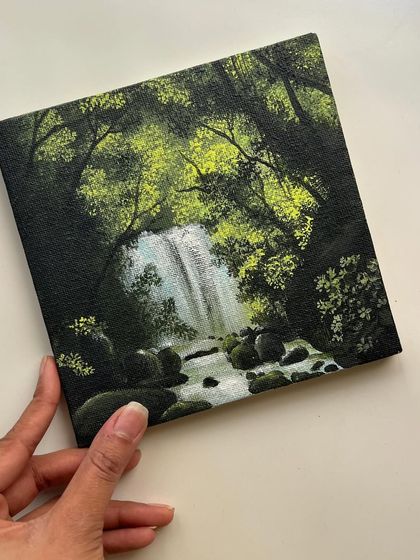 Holding the finished mini waterfall painting. It’s a small piece of tranquility that can brighten any space.