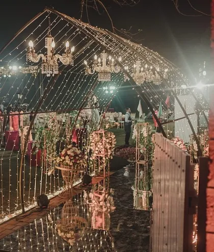 A wider perspective of the Sangeet entrance, showing the mirrored walkway reflecting the lights and creating a feeling of infinite sparkle and grandeur.