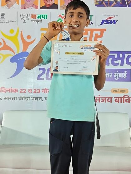 A champion's smile. Swaransh proudly bites his gold medal, a classic pose that captures the joy and satisfaction of his victory at the Khasdar Chashak 2025 competition.