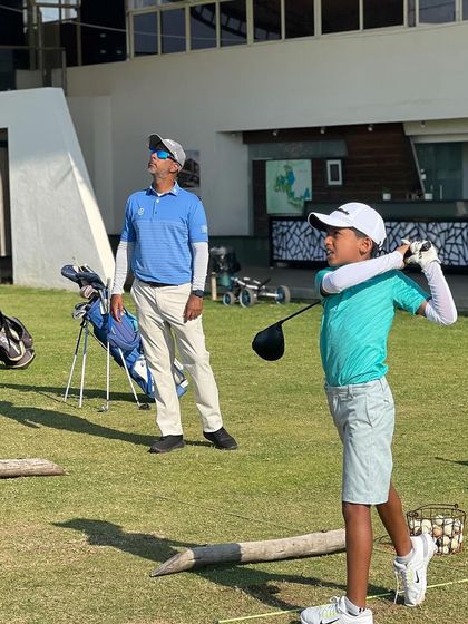 A coach watches a young player's drive. This talented junior has shown remarkable progress in just a few months with us.
