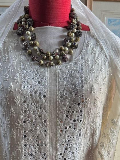 A close-up of the neckline, styled with a traditional necklace.
