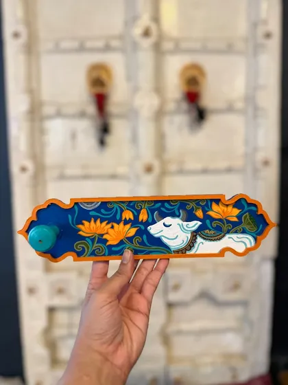 A beautiful hand-painted incense holder featuring a serene Pichwai-style cow among lotus flowers.