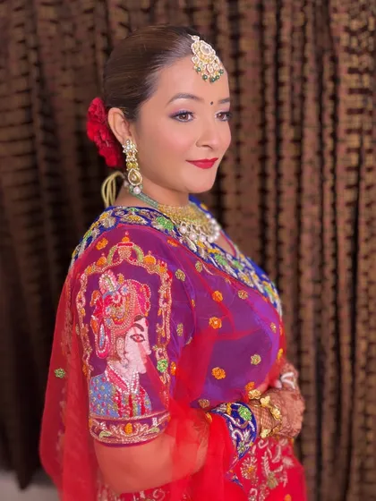 A side view of the sleek twisted bun, showing the clean lines and the beautiful contrast with the red flowers and the bride's embroidered blouse.