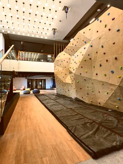 An office recreation zone featuring a large, professional-grade rock climbing wall. This is a unique amenity that promotes health and wellness.