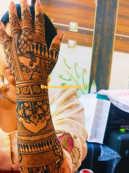 A client showing off her beautiful bridal mehandi. The design is full of traditional peacock and lotus motifs, covering her arm.