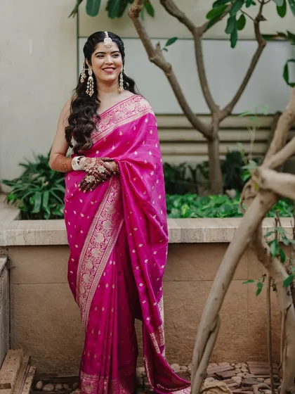 A full-length view of Reeya's vibrant pink saree for her Haldi. The simple, elegant makeup allows the bold outfit and jewelry to shine.
