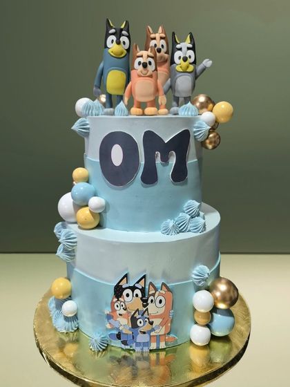 A two-tiered cake celebrating the popular cartoon 'Bluey'. It features the entire Heeler family as toppers and decorations, making it a hit with young fans.