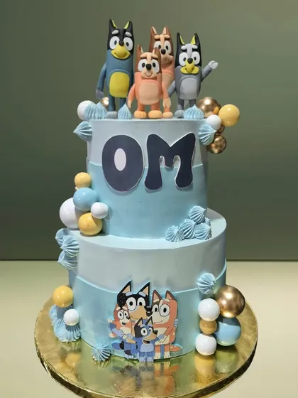 A two-tiered cake celebrating the popular cartoon 'Bluey'. It features the entire Heeler family as toppers and decorations, making it a hit with young fans.