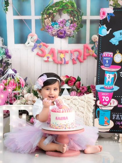 A close-up of the birthday girl with her cake and milestone board. This shot captures all the key elements of a personalized first birthday session.