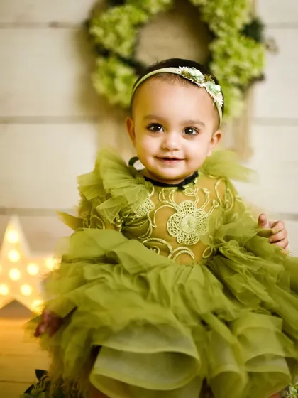 A close-up portrait from the first birthday session. Her sweet smile and the lovely details of her ruffled green dress are the focus of this beautiful shot.