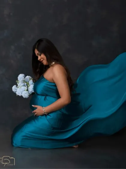 The flowing teal fabric creates a sense of movement and drama in this beautiful kneeling portrait. A truly artistic and elegant shot.
