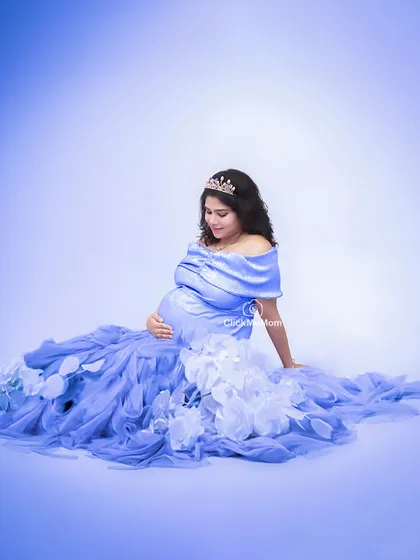 Feeling like royalty in a dreamy periwinkle blue gown. The soft tulle and off-shoulder design add a touch of romance, while the tiara completes this princess-inspired maternity look.