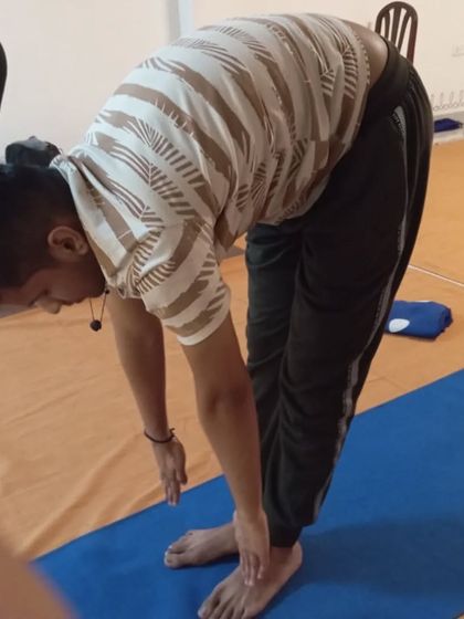 A participant in Padahastasana, a forward-bending posture that is a key component of the Surya Kriya sequence.