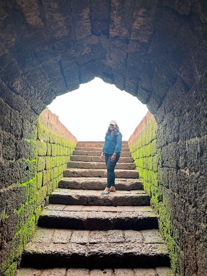 A trekker posing in the stone archway of Mirjan Fort.