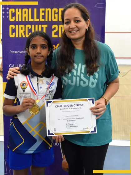 A young athlete proudly displays her medal and certificate of achievement at the Challenger Circuit awards ceremony.