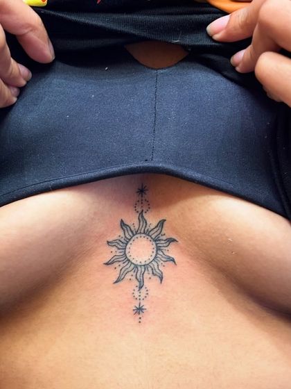 A delicate sun tattoo on the sternum. This is a great example of a small, meaningful piece in a popular placement, done with clean dot work and fine lines.