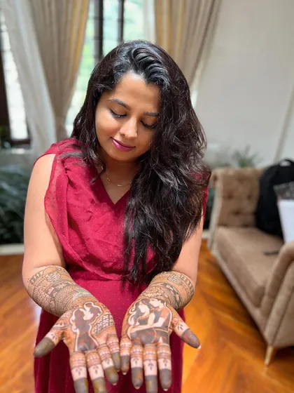 The joy of a mom-to-be admiring her custom mehendi. The design includes portraits of her and her partner, making her Seemantha celebration even more special.