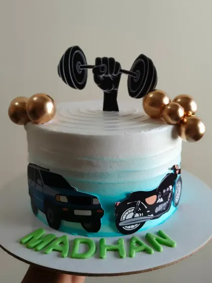 A cake for someone who loves fitness, cars, and bikes. This design features a barbell, a car, and a motorcycle.