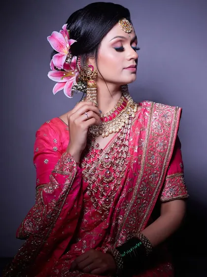 An elegant portrait of a bride in a pink saree, her hair adorned with a beautiful lily. This look is perfect for a reception or engagement.