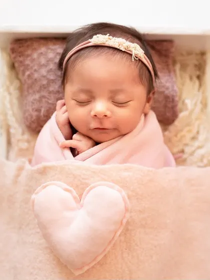 A close-up of a sleeping newborn swaddled in a soft pink blanket with a heart detail. Simple, sweet, and full of love.