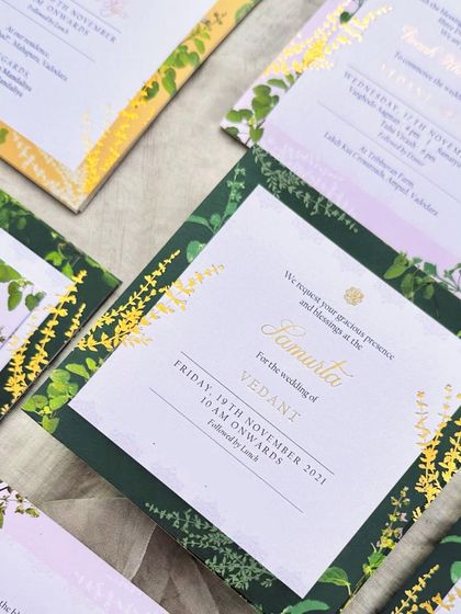 A detail of the 'Samarta' ceremony invitation. The design features a border of illustrated Tulsi leaves and flowers, with gold foil accents that catch the light beautifully.