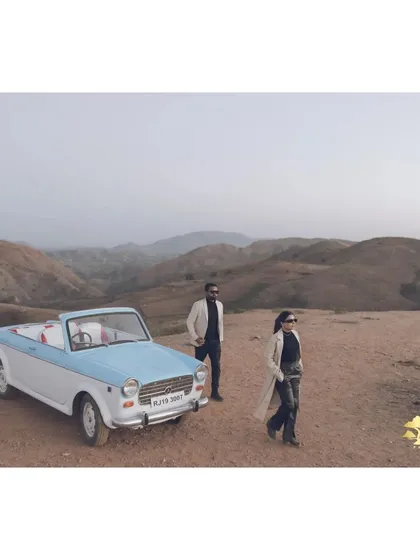 A wide shot that captures the cinematic feel of a road trip adventure. The vintage car and vast landscape make for an epic pre-wedding photo.
