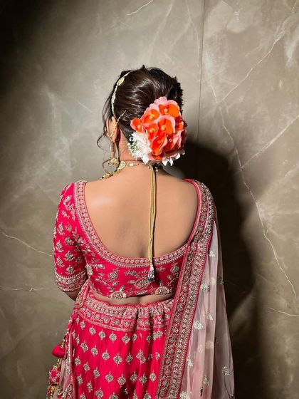 A close-up of a textured bridal bun. I used fresh orange and white flowers to create a vibrant and beautiful accessory that complements the bride's red lehenga.