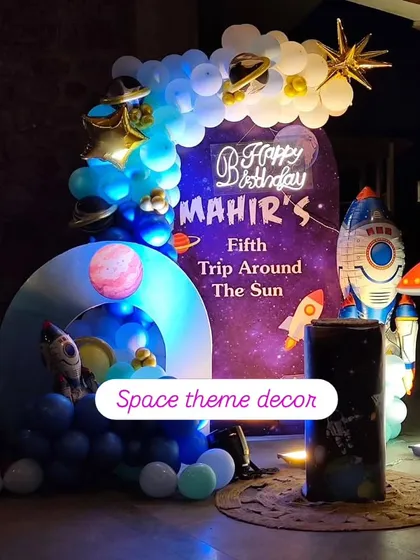 An out-of-this-world space-themed birthday party, complete with a galaxy backdrop, planet cutouts, rocket ship props, and a custom neon sign for the birthday boy.
