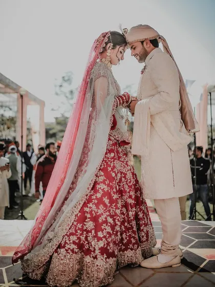 A quiet, intimate moment between the bride and groom during their outdoor wedding ceremony. The backlighting from the sun creates a beautiful, ethereal glow, highlighting this special connection.