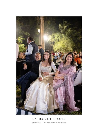 The sister of the bride with her parents. Her modern ivory lehenga provides a beautiful contrast to her mother's traditional pink saree, showing a blend of generational styles.
