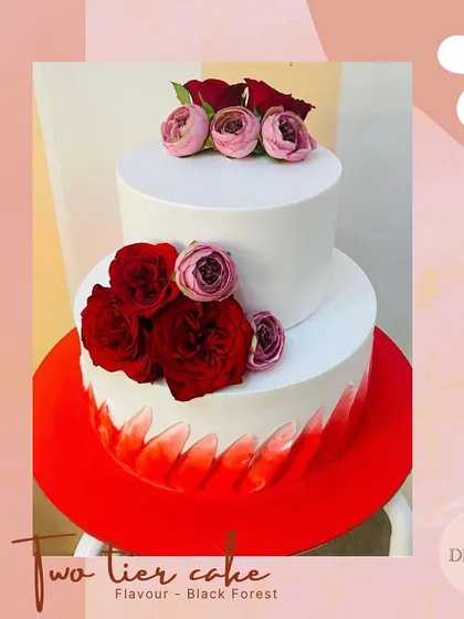 A modern and striking two-tier Black Forest wedding cake. The clean white top tier contrasts beautifully with the red brushstroke effect on the bottom, all tied together with deep red roses.