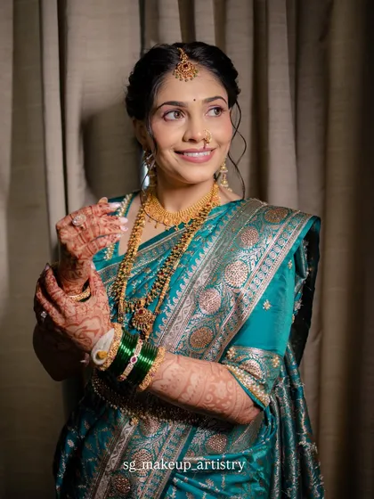 A poised and elegant portrait. The bride's makeup is soft yet defined, perfectly complementing her beautiful teal green silk saree and traditional gold jewelry.